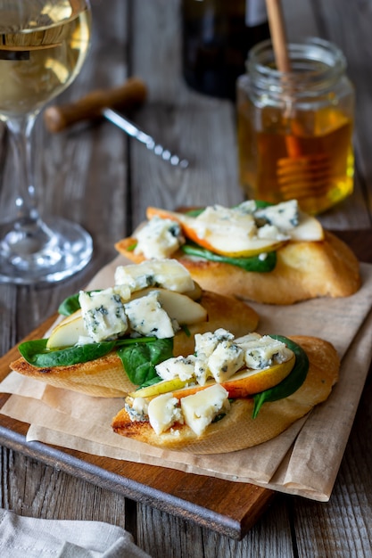 Bruschetta met spinazie, peer en blauwe kaas. Wijn. Vegetarisch eten. Gezond eten. Veganisme. Eetpatroon.