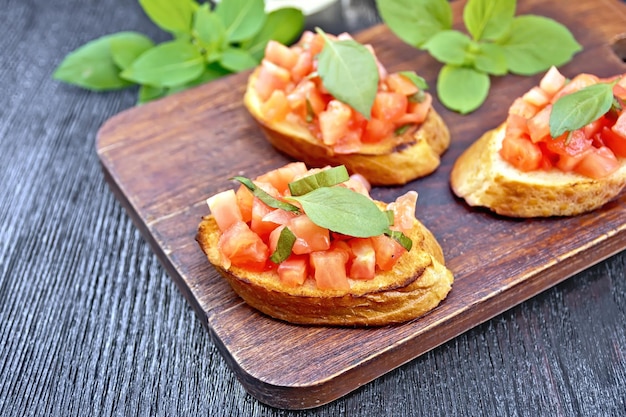 Bruschetta met tomaat en basilicum op donker houten bord