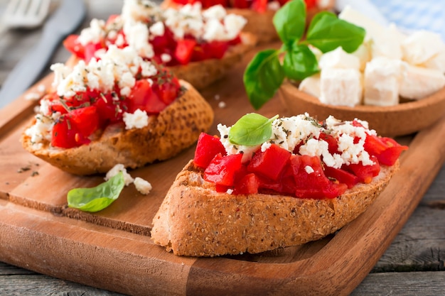 Bruschetta met tomaten, fetakaas en basilicum. Traditionele Griekse snack op houten oppervlak. Selectieve aandacht.