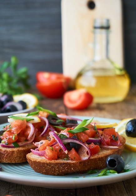 Bruschetta met tomaten, olijven en rode uien op een plaat