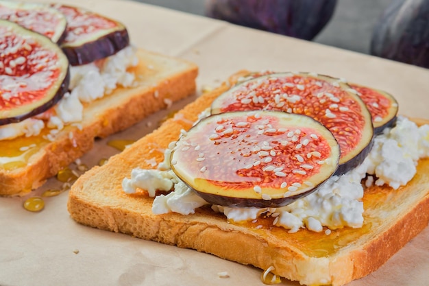 Bruschetta met vijgen, honing, sesamzaadjes en verse zachte kaas op ambachtelijke papieren backing close-up selectieve focus op toast