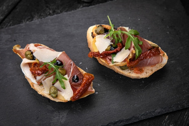 Bruschetta met vlees op een donkere houten tafel