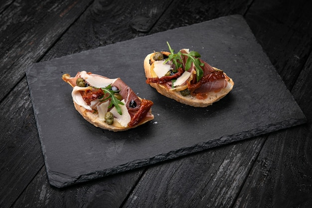 Bruschetta met vlees op een donkere houten tafel