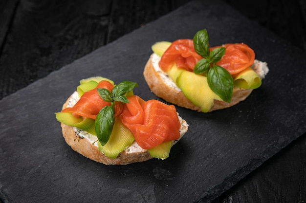 Bruschetta met zalm en avocado op een donkere houten tafel