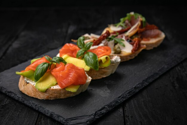 Bruschetta met zalm en vlees op een donkere houten tafel