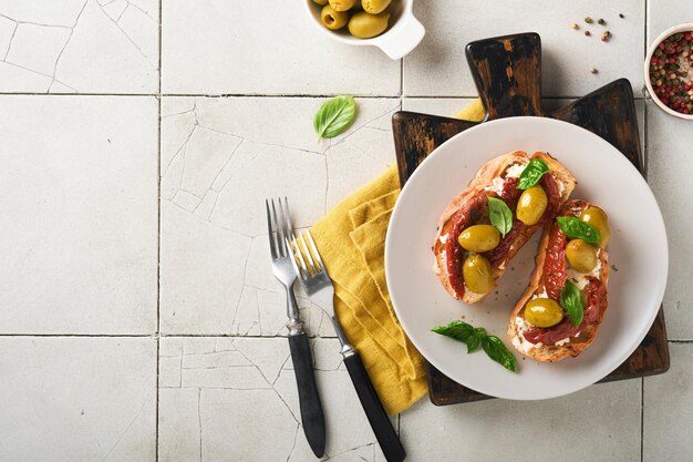 Bruschetta met zongedroogde tomaten Toast of sandwich met ricotta zongedroogde tomaten en Provençaalse kruiden met basilicum geserveerd op een bord op een grijze oude gebarsten tegeltafel Bovenaanzicht banner menu recept