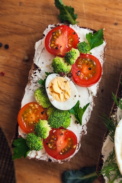 Bruschetta op donker brood kwark helften cherrytomaatjes stukjes broccoli peterselie en kruiden