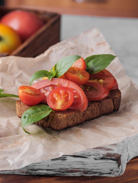 Bruschetta op zwart brood met tomaten en basilicum.