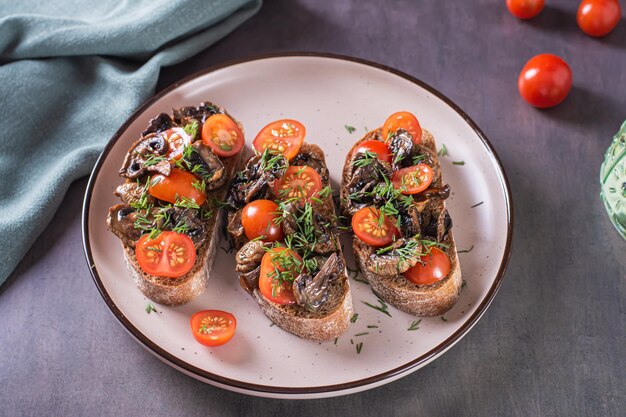 Брускетта на ржаной чиабатте с помидорами черри и жареными грибами на тарелке