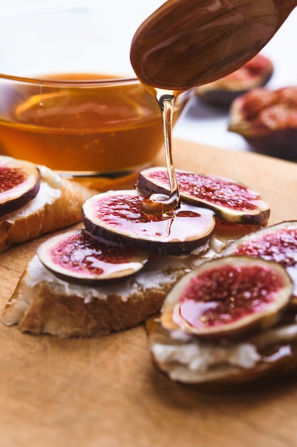 Bruschetta's met vijgen, zachte kaas en honing op een houten bord.