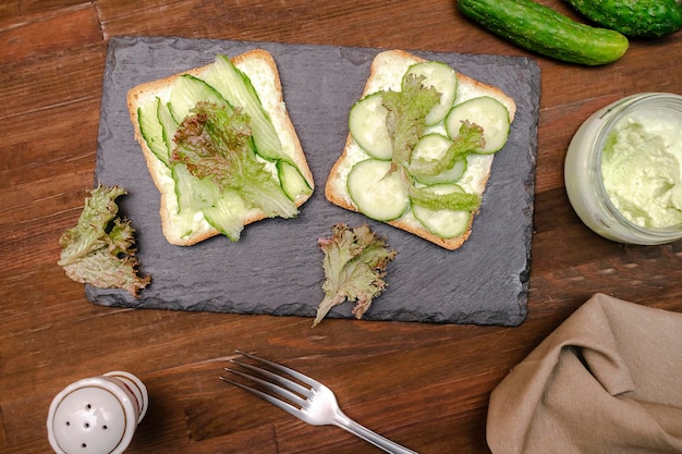 Bruschetta sandwich brood toast met zachte groene avocado kaas ricottafresh komkommers basilicum groen op houten snijplank Lekker gezond vegetarisch etenItaliaanse keuken voorgerecht bovenaanzicht plat lag