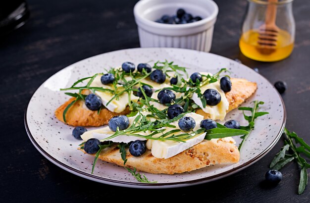 Bruschetta. toast crostini met verse bessen bosbessen en honing, brie kaas, rucola. italiaanse keuken