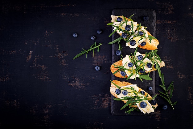 Bruschetta. crostini di pane tostato con bacche fresche di mirtillo e miele, brie, rucola. vista dall'alto, .