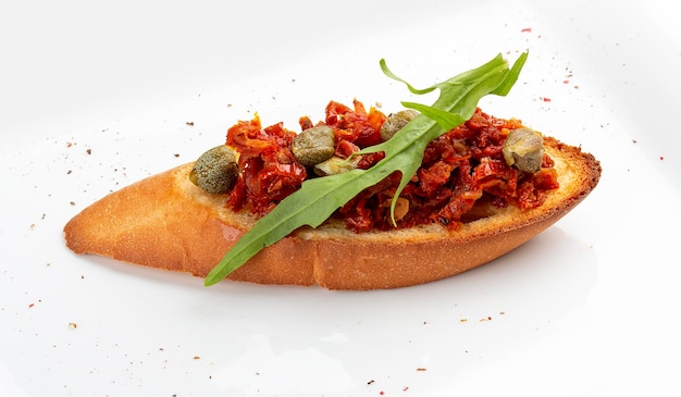 Bruschetta with baked peppers and capers on a white plate