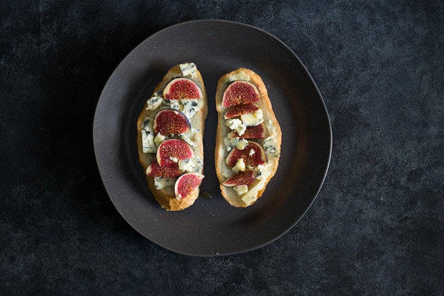 Bruschetta with blue cheese and fresh figs on dark background