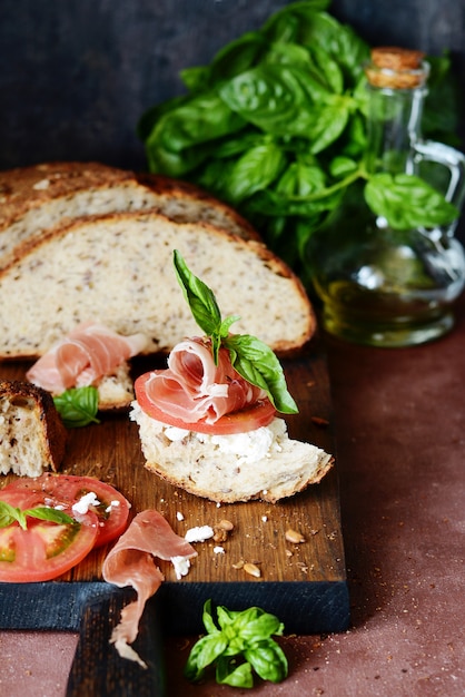 Брускетта с сушеным хамоном, сливочным сыром, помидорами и свежим базиликом.