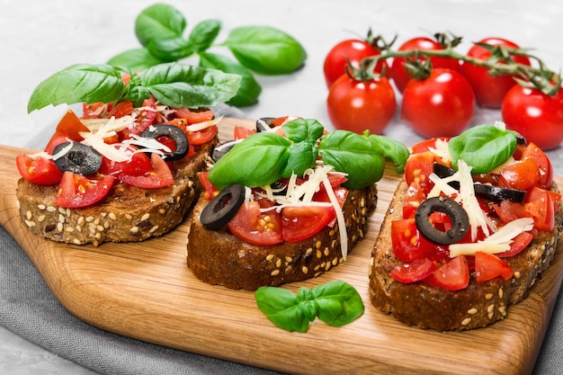 Bruschetta with fresh tomato basil cheese and olive on grey background