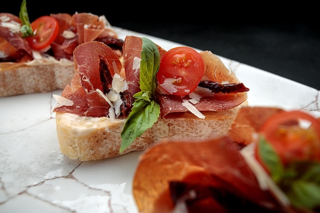 Bruschetta with parma and sauce on a plate on a dark background