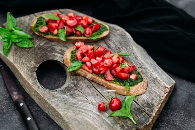 Bruschetta with pesto and tomatoes on a dark background