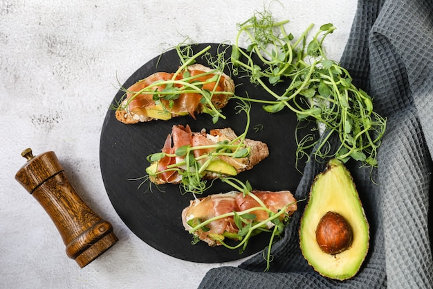 Foto bruschetta con prosciutto e crema di formaggio e meecrogreens. pane con pancetta affumicata e crema di formaggio.