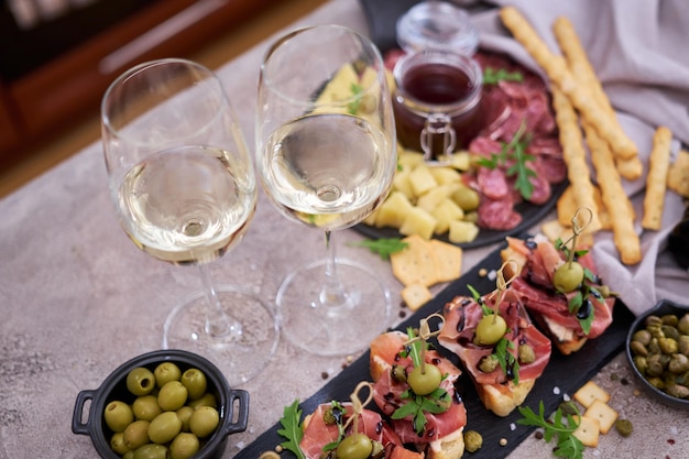 Bruschetta with prosciutto ham and capers with traditional antipasto meat plate on background