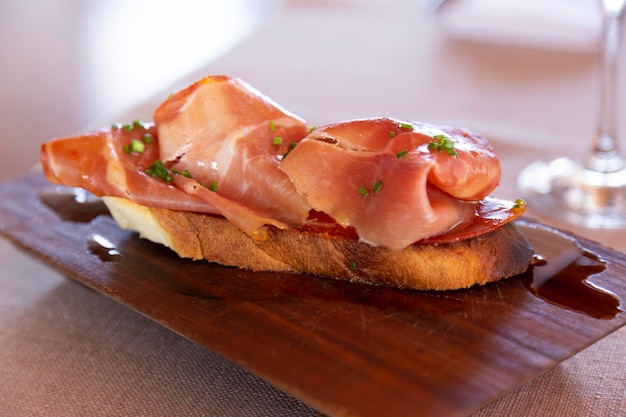 Bruschetta with prosciutto and microgreens with olive oil. Wood plate closeup