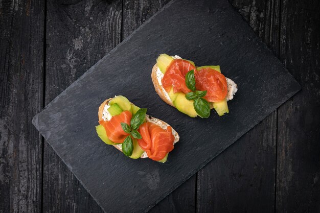 Bruschetta with salmon and avocado on a dark wooden table