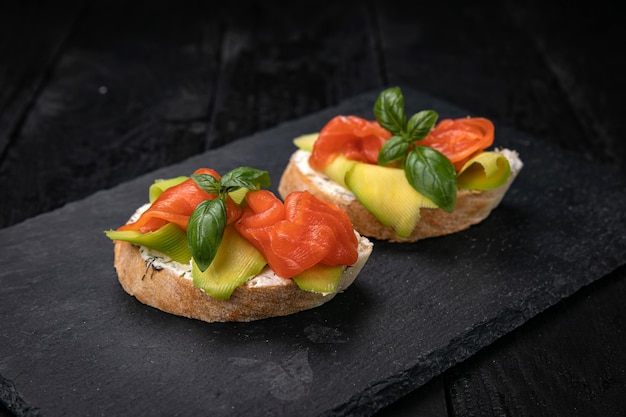 Foto bruschetta con salmone e avocado su un tavolo di legno scuro