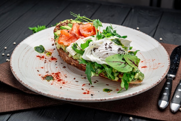 Bruschetta with sliced avocado feta cheese pesto sauce poached egg and salted salmon