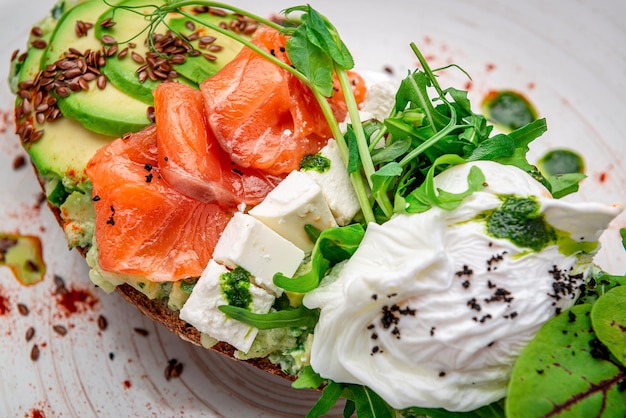 Bruschetta with sliced avocado feta cheese pesto sauce poached egg and salted salmon