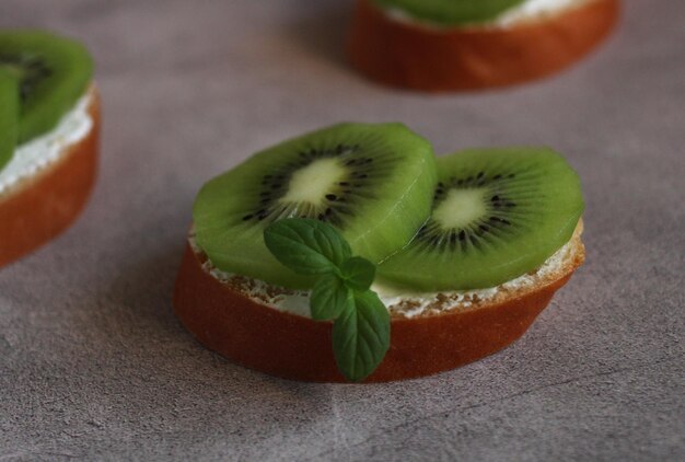 Bruschetta with soft cheese and kiwi on a gray background