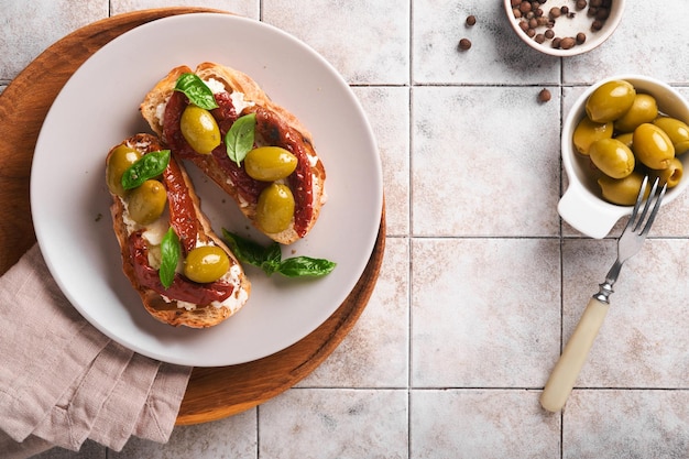 Bruschetta con pomodori secchi toast o panino con ricotta pomodori secchi ed erbe di provenza con basilico servito su un piatto su un vecchio tavolo grigio piastrellato incrinato ricetta del menu banner vista dall'alto