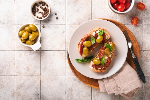 Bruschetta with sun dried tomatoes Toast or sandwich with ricotta sun dried tomatoes and Provence herbs with basil servered on a plate on a grey old cracked tile table Top view banner menu recipe