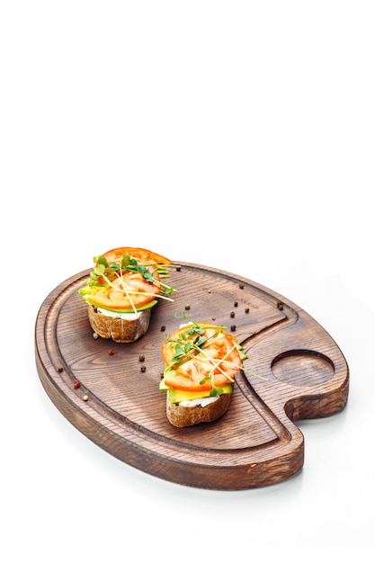 Photo bruschetta with tomato cream cheese and avocado lies