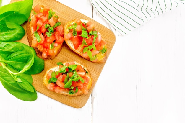 Photo bruschetta with tomato and spinach on light board top