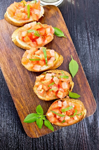 Bruschetta with tomatoes and basil on a wooden board background from abovexA