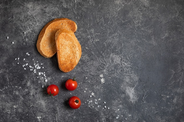 Foto bruschetta con i pomodori nelle mani su un fondo scuro, vista superiore.