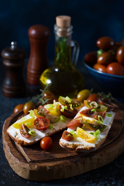 Bruschetta with tomatoes and olive oil on a wooden board -\
traditional italian, spanish snack, selective focus