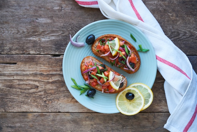 Bruschetta with tomatoes, olives and red onions on a plate