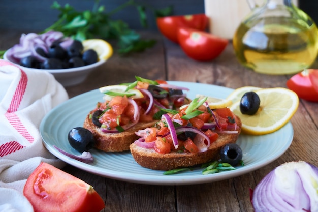 Bruschetta with tomatoes, olives and red onions on a plate