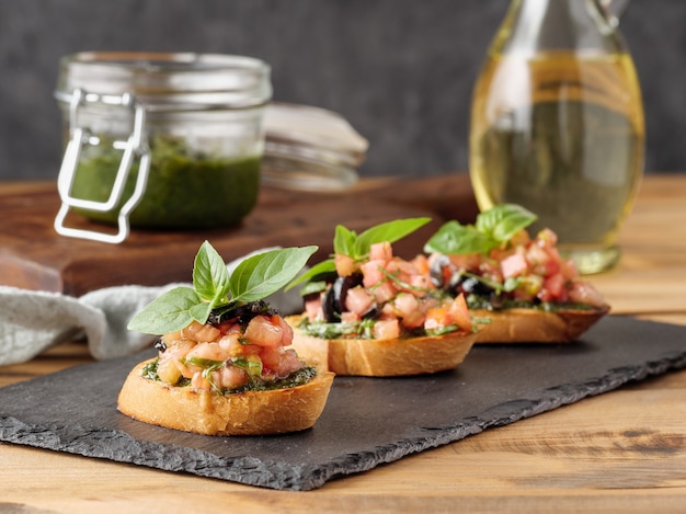 Bruschetta with tomatoes and pesto on a wooden table. Copy space.
