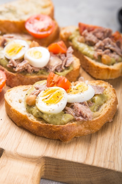 Bruschetta with tuna, tomato, egg, and avocado spread.