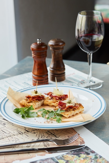 Bruschetta on a wooden table in a white plate and a glass of red wine