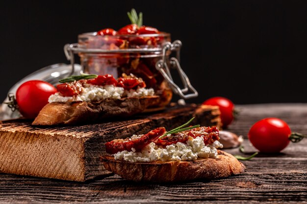 Bruschettas with sun dried tomatoes and ricotta diet cheese on a wooden background.