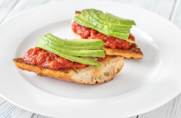 Bruschettas with tomato spread and slices of avocado