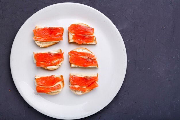 Bruschettes met boter en zalm op een witte plaat op een grijze betonnen ondergrond