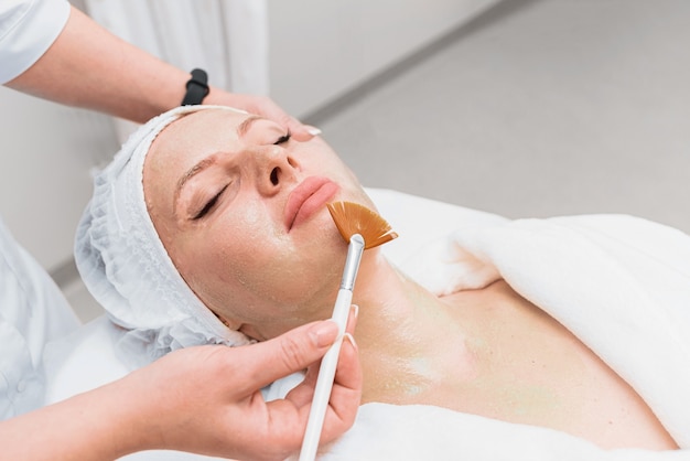 Brush application of an enzyme mask to a woman's face.