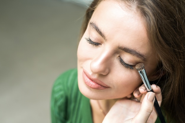 Brush applying beige makeup