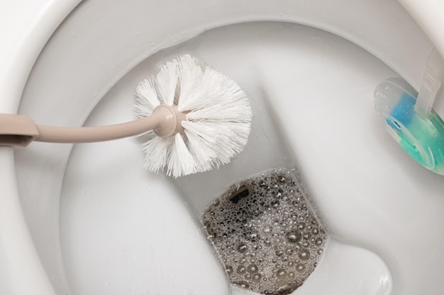 Brush cleans a white toilet close up