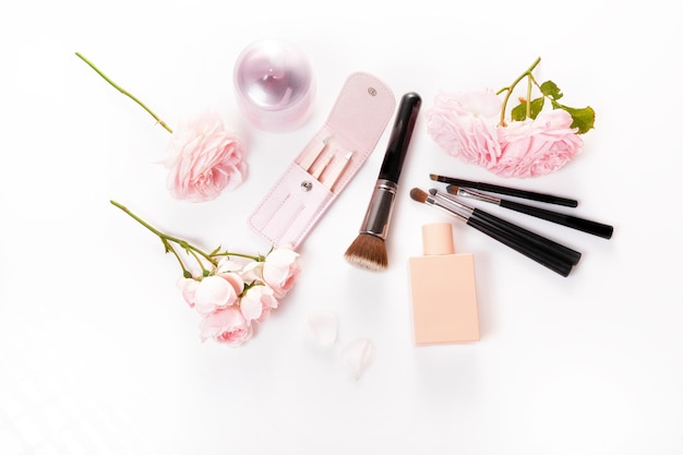 Brush, cosmetic and pink rose on a white background, beauty and makeup concept